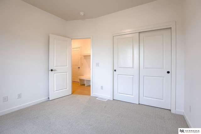 unfurnished bedroom with a closet and light carpet