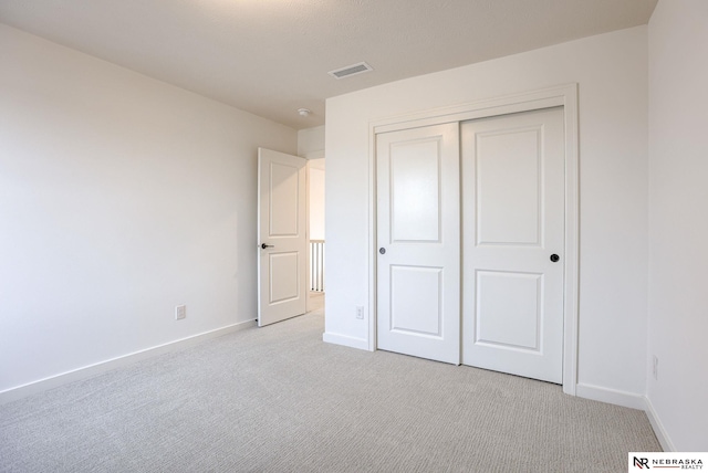 unfurnished bedroom featuring light carpet and a closet