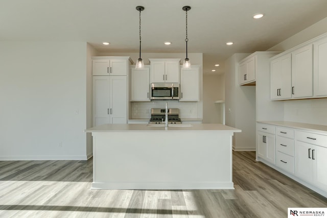 kitchen with pendant lighting, white cabinetry, a center island with sink, and stainless steel appliances