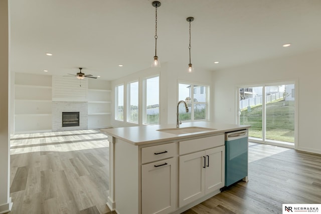 kitchen featuring white cabinets, a center island with sink, stainless steel dishwasher, and a healthy amount of sunlight