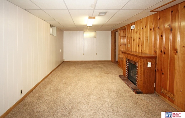 basement with wooden walls, carpet, and a brick fireplace