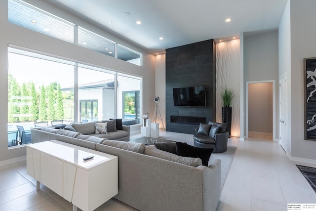 living room featuring a fireplace, a towering ceiling, and light tile patterned flooring