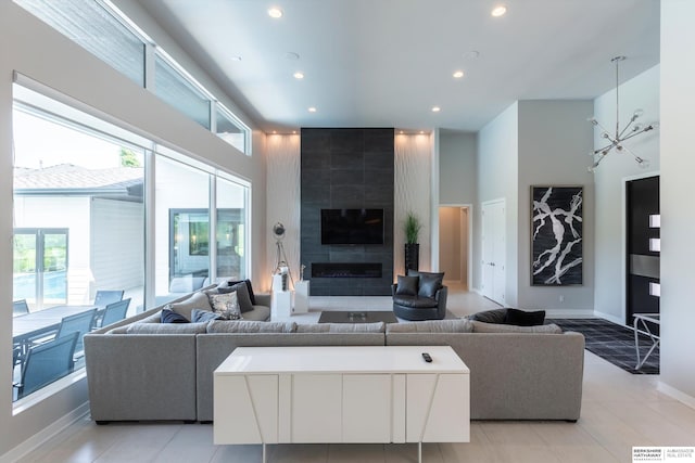 living room featuring a tiled fireplace, a towering ceiling, and light tile patterned flooring