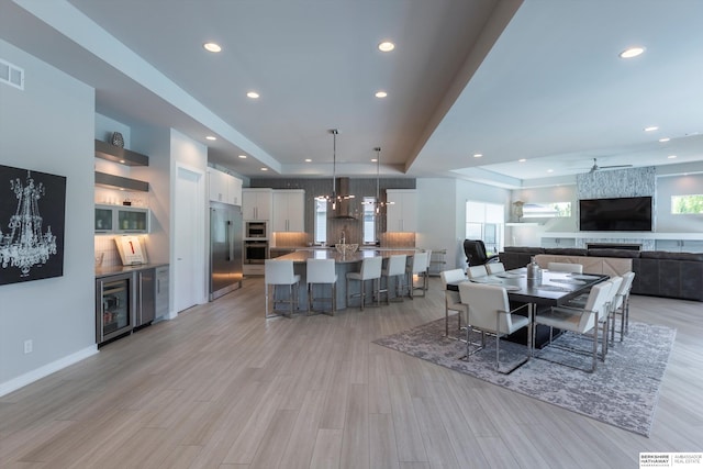 dining space with wine cooler, light hardwood / wood-style flooring, and ceiling fan