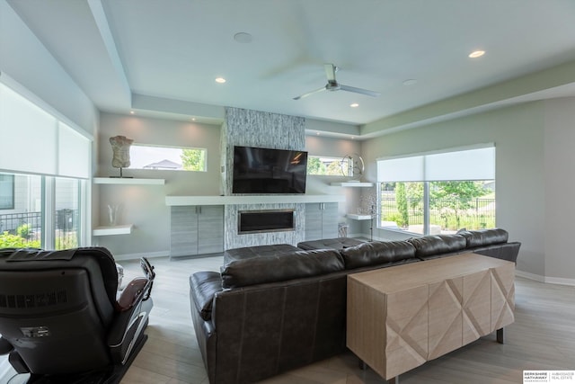 living room with ceiling fan, a fireplace, and light hardwood / wood-style flooring