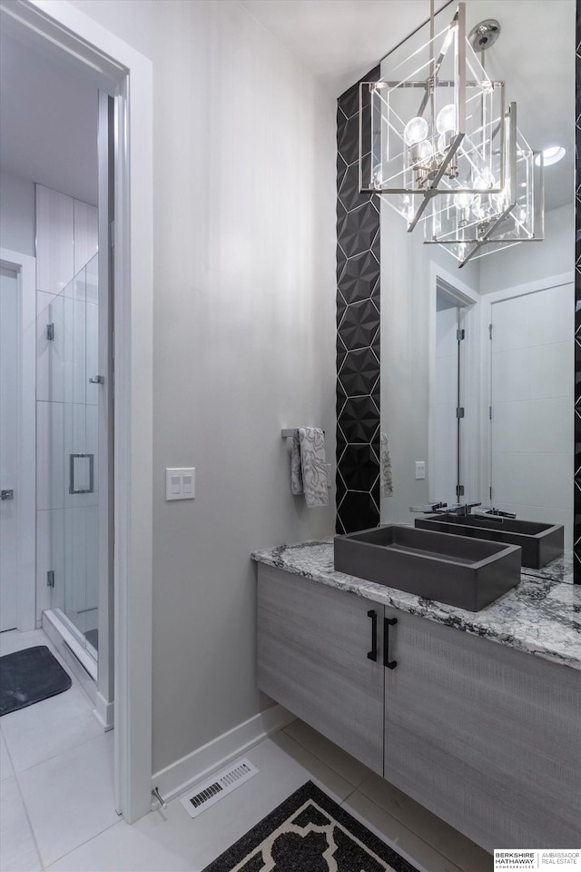 bathroom featuring tile patterned flooring, vanity, a chandelier, and a shower with shower door