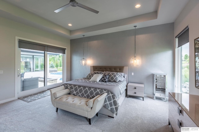 carpeted bedroom featuring access to outside, ceiling fan, and a tray ceiling