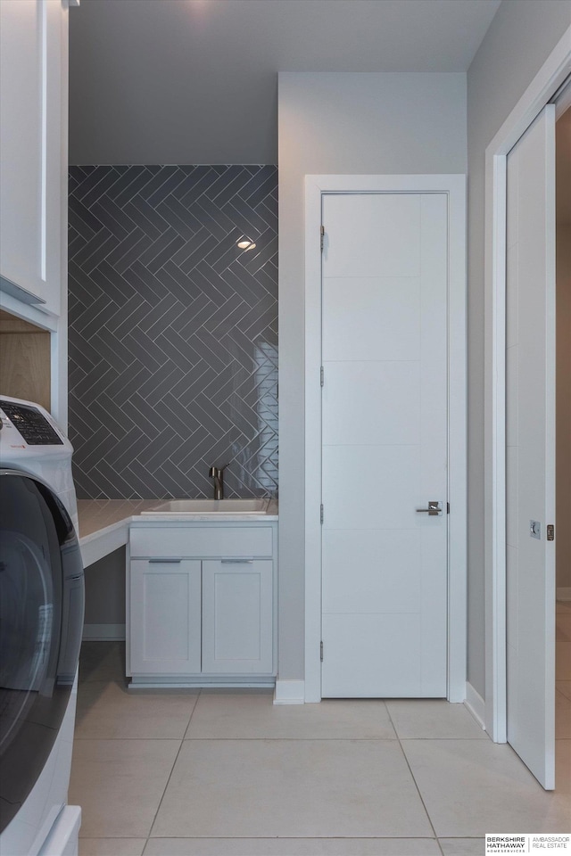 washroom featuring cabinets, sink, tile walls, washer / clothes dryer, and light tile patterned flooring