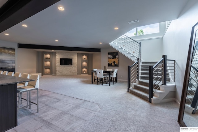 carpeted living room with a stone fireplace