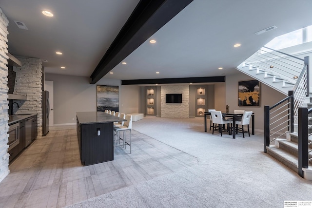 kitchen with a kitchen bar, stainless steel appliances, light colored carpet, sink, and a kitchen island