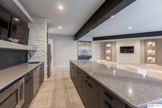 kitchen with light stone countertops, sink, a large island, and appliances with stainless steel finishes