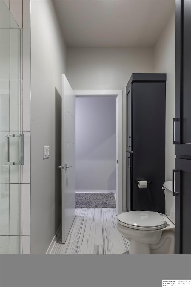 bathroom featuring toilet and a shower with shower door