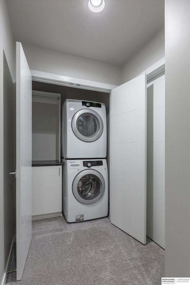 laundry area featuring light carpet and stacked washer and clothes dryer