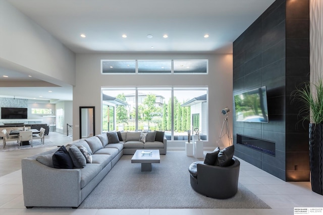 tiled living room featuring a tile fireplace and a high ceiling