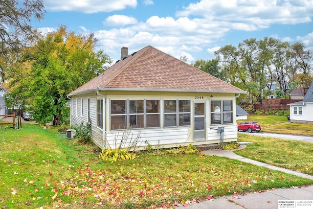 bungalow featuring a sunroom, central AC unit, and a front yard