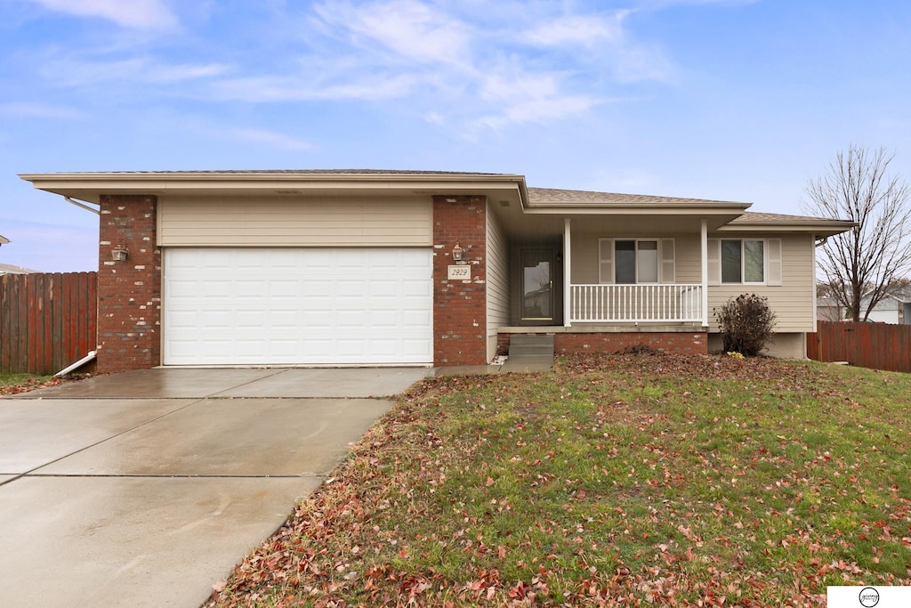 ranch-style home with a porch, a front yard, and a garage