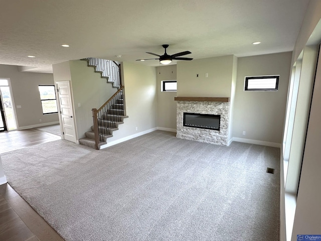 unfurnished living room featuring carpet, ceiling fan, and a fireplace