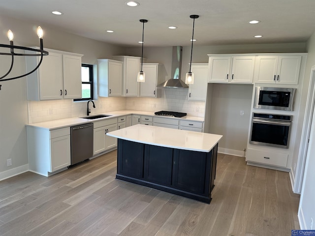 kitchen featuring a center island, sink, wall chimney exhaust hood, white cabinetry, and stainless steel appliances