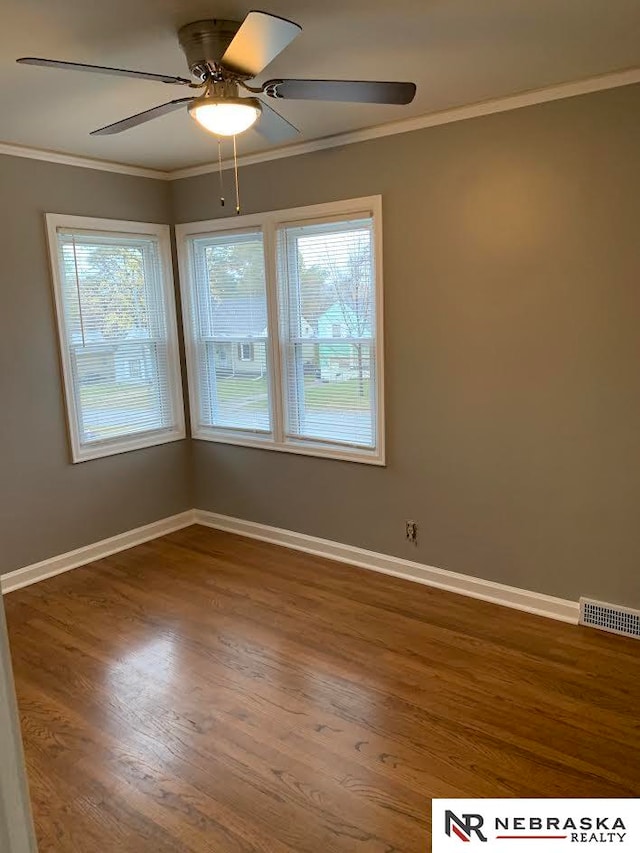 empty room with ceiling fan, ornamental molding, a healthy amount of sunlight, and wood-type flooring