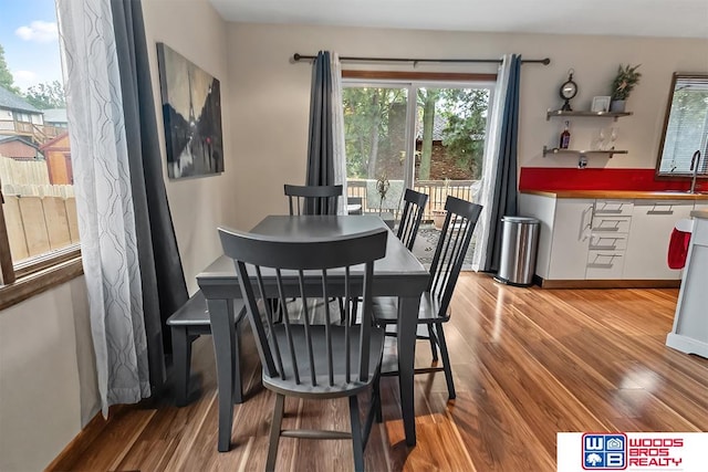 dining room featuring a healthy amount of sunlight, wood-type flooring, and sink