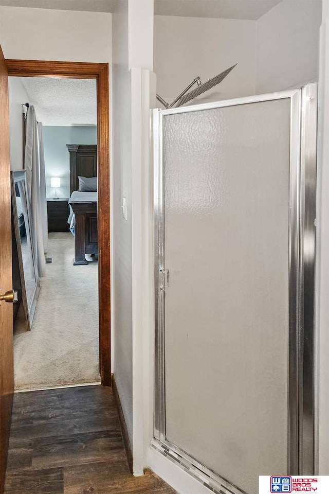 bathroom featuring hardwood / wood-style floors, a textured ceiling, and a shower with door