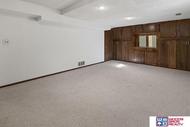 carpeted empty room with beam ceiling and a textured ceiling