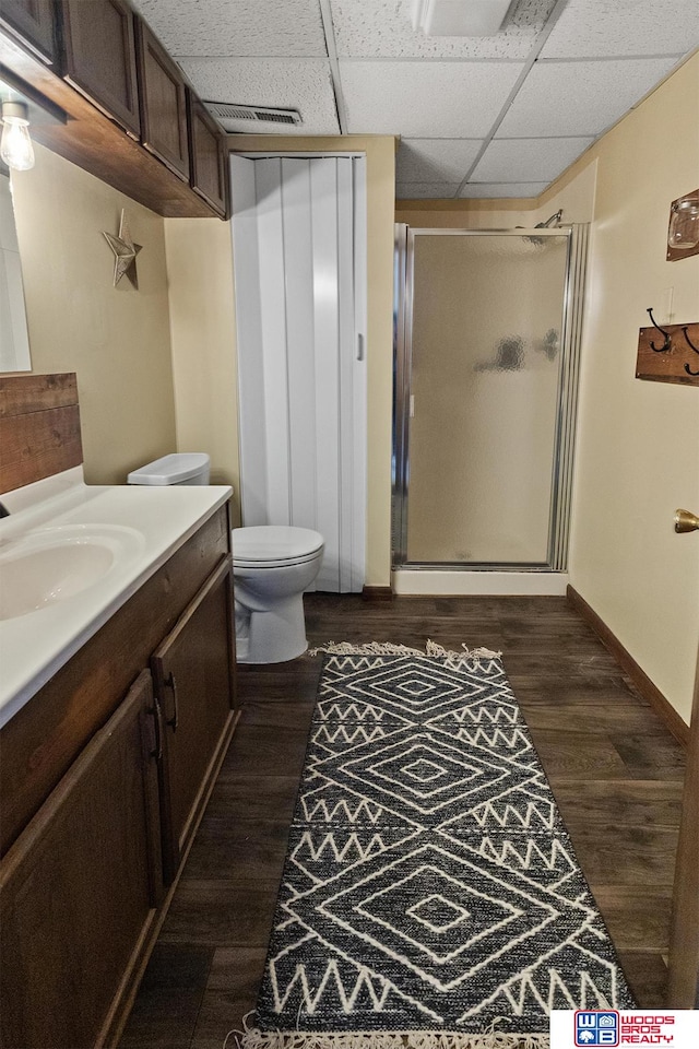 bathroom featuring walk in shower, wood-type flooring, toilet, a paneled ceiling, and vanity