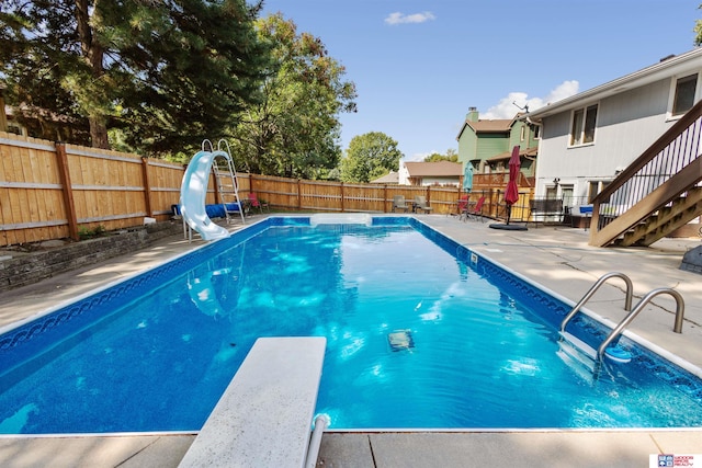 view of swimming pool with a diving board and a water slide