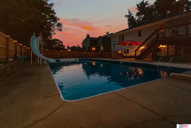 pool at dusk featuring a water slide