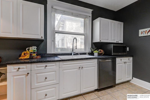 kitchen featuring appliances with stainless steel finishes, light tile patterned floors, white cabinetry, and sink