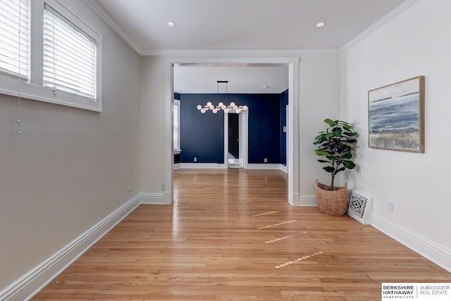 hallway with an inviting chandelier, ornamental molding, and light hardwood / wood-style flooring