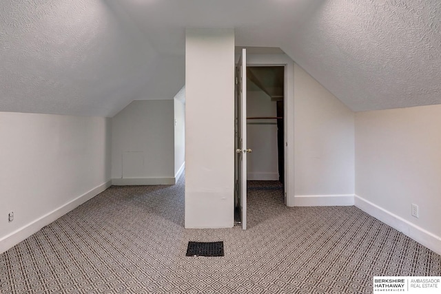 bonus room featuring light carpet, a textured ceiling, and vaulted ceiling