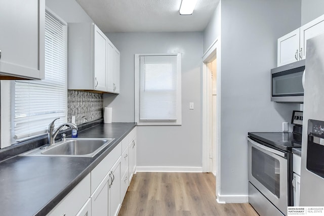 kitchen featuring sink, light hardwood / wood-style flooring, a textured ceiling, white cabinets, and appliances with stainless steel finishes