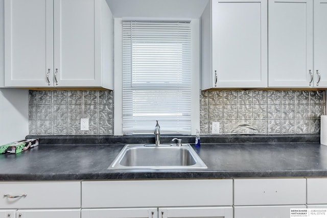 kitchen with tasteful backsplash, white cabinetry, and sink