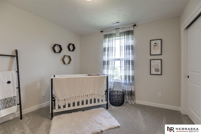 bedroom with carpet, a textured ceiling, and a crib