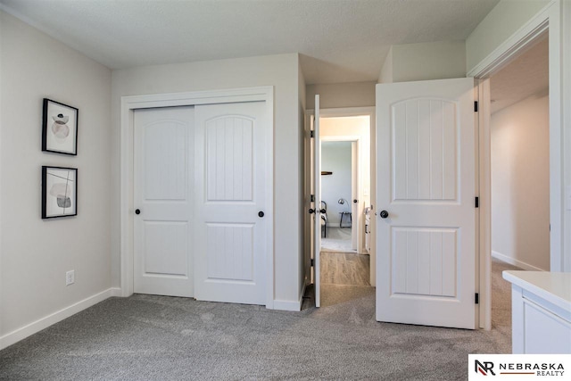 unfurnished bedroom featuring light carpet, a closet, and a textured ceiling