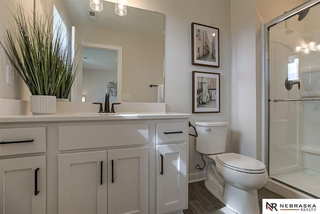 bathroom with toilet, a shower with door, vanity, and hardwood / wood-style flooring