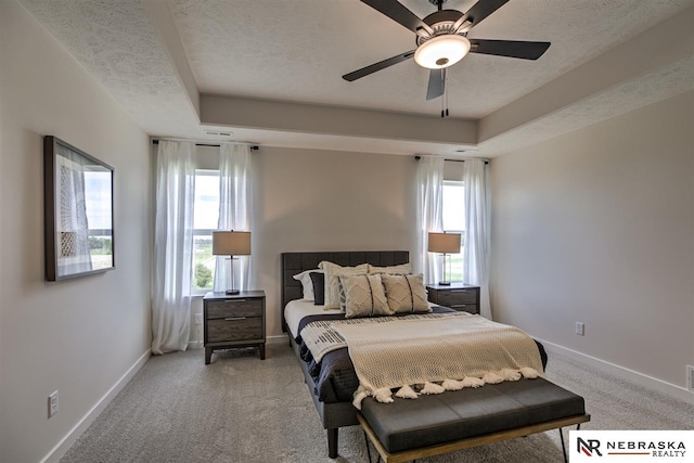 bedroom with ceiling fan, a raised ceiling, carpet floors, and a textured ceiling