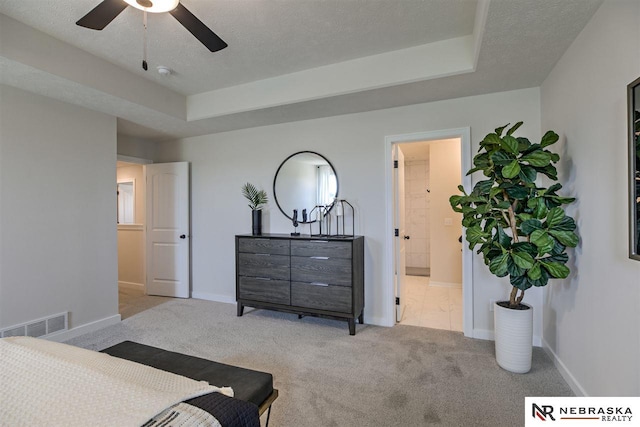 carpeted bedroom featuring ceiling fan, a textured ceiling, connected bathroom, and a tray ceiling