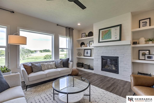 living room featuring a fireplace, a textured ceiling, light wood-type flooring, and plenty of natural light