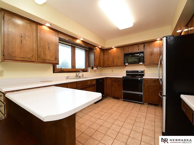 kitchen with light tile patterned floors, kitchen peninsula, a textured ceiling, black appliances, and sink