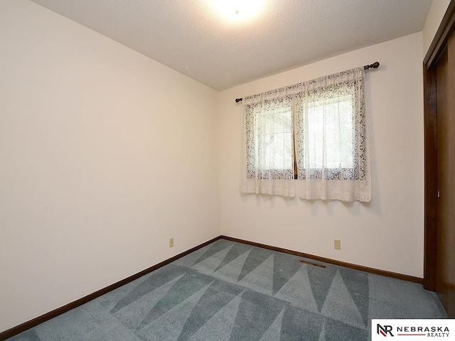 carpeted empty room featuring a textured ceiling