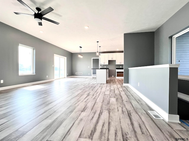 unfurnished living room featuring ceiling fan, light wood-type flooring, and sink