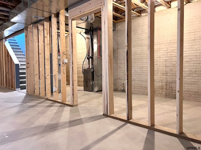 basement featuring brick wall and heating unit