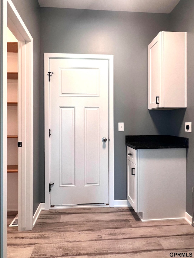 clothes washing area with hookup for an electric dryer and light wood-type flooring