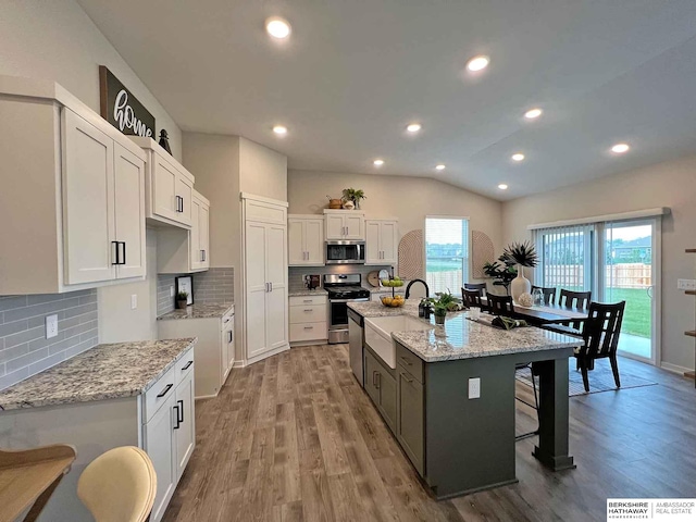 kitchen featuring light hardwood / wood-style floors, white cabinetry, stainless steel appliances, and a kitchen island with sink