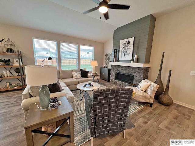 living room with a stone fireplace, ceiling fan, light hardwood / wood-style floors, and lofted ceiling