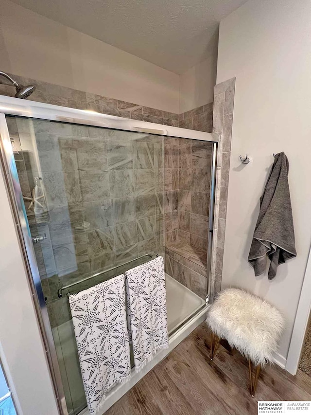 bathroom with a shower with door and wood-type flooring