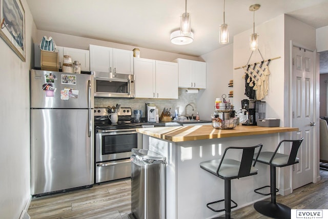 kitchen featuring butcher block counters, white cabinets, light hardwood / wood-style floors, and appliances with stainless steel finishes