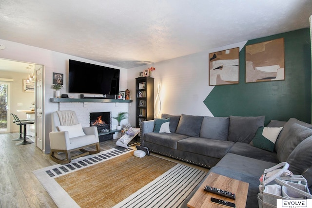 living room with a textured ceiling, light hardwood / wood-style floors, and a brick fireplace